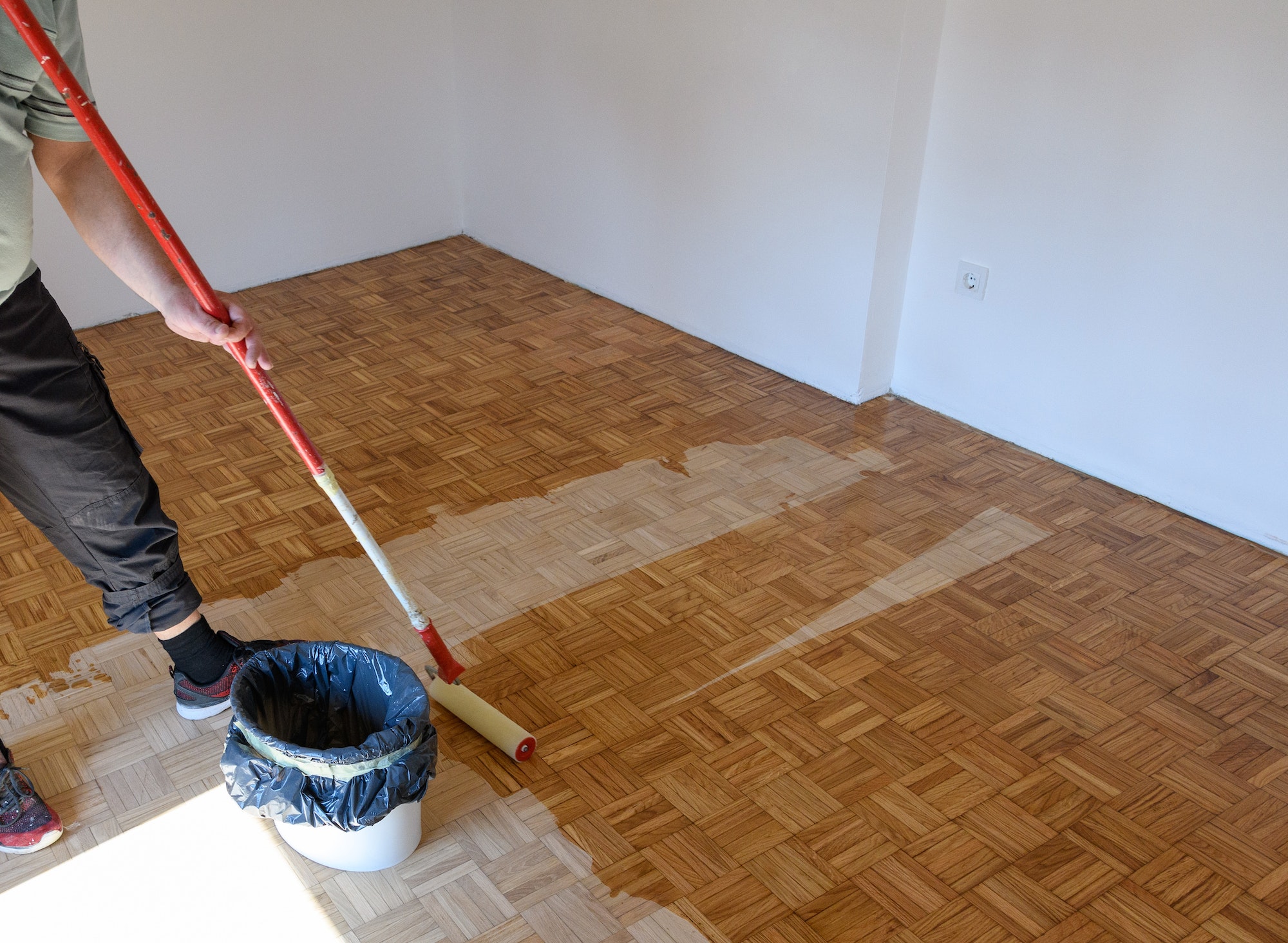 Man applying lacquer finish on oak hardwood floor